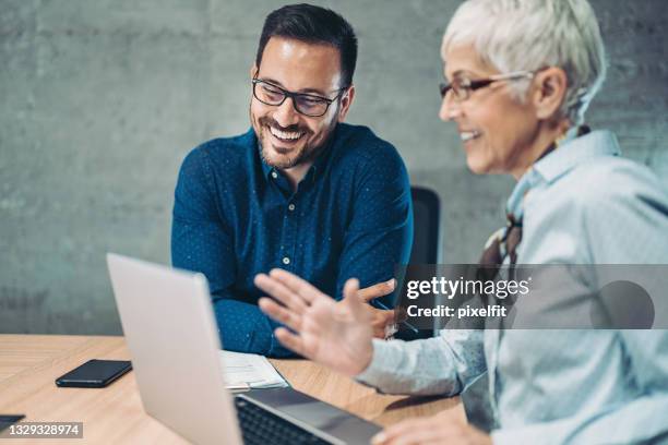 senior geschäftsfrau im gespräch mit einem jungen kollegen - business consulting stock-fotos und bilder