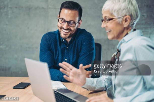 senior businesswoman talking to a young colleague - role model stock pictures, royalty-free photos & images