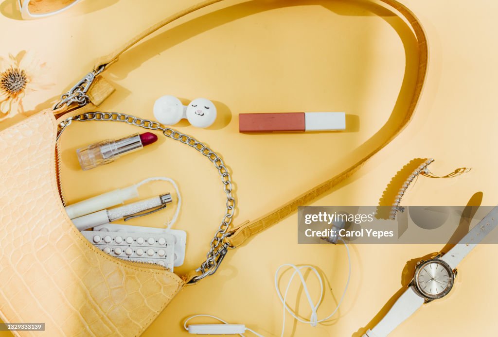 Contents of woman bag in yellow background.Top view