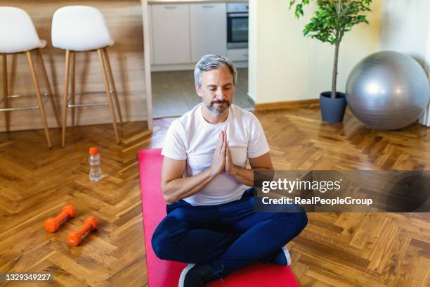 handsome mature man practicing zen yoga at home - lotus position stock pictures, royalty-free photos & images