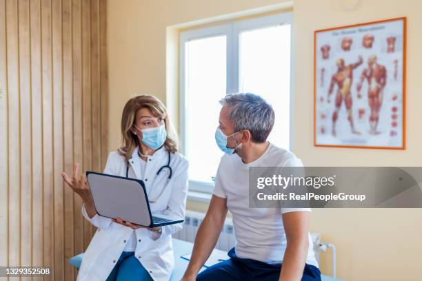 photo of a female mature  doctor with a protective face mask taking anamnesis from her mature patient - prince william duke of cambridge visits the isle of man stockfoto's en -beelden