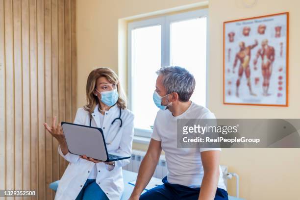 photo of a female mature  doctor with a protective face mask taking anamnesis from her mature patient - patient visit stock pictures, royalty-free photos & images