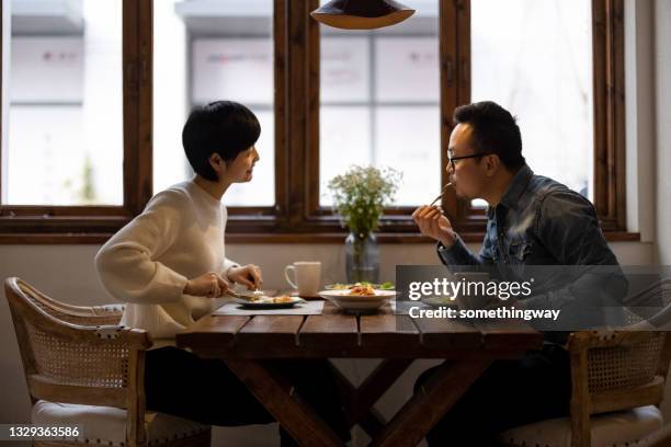 a couple eating in a restaurant - mid adult couple stockfoto's en -beelden