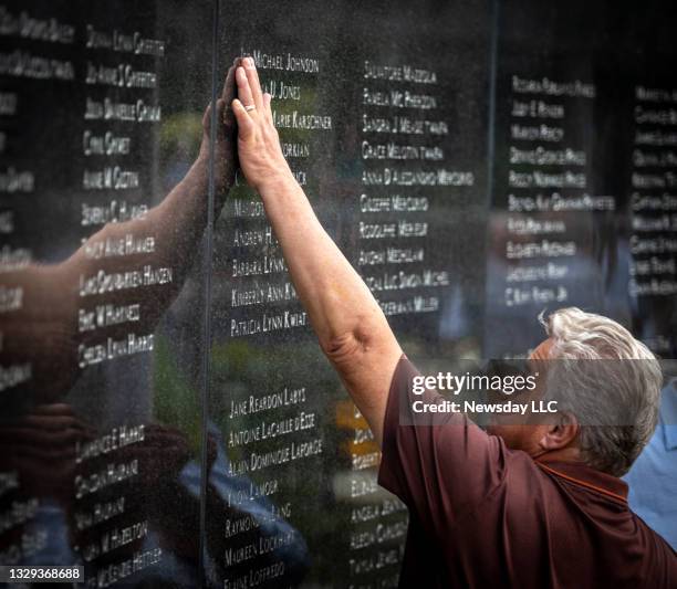 Family member touches the name of a loved one at Flight TWA 800 Memorial, in Mastic Beach, New York, on July 17 for the 25th anniversary of the plane...