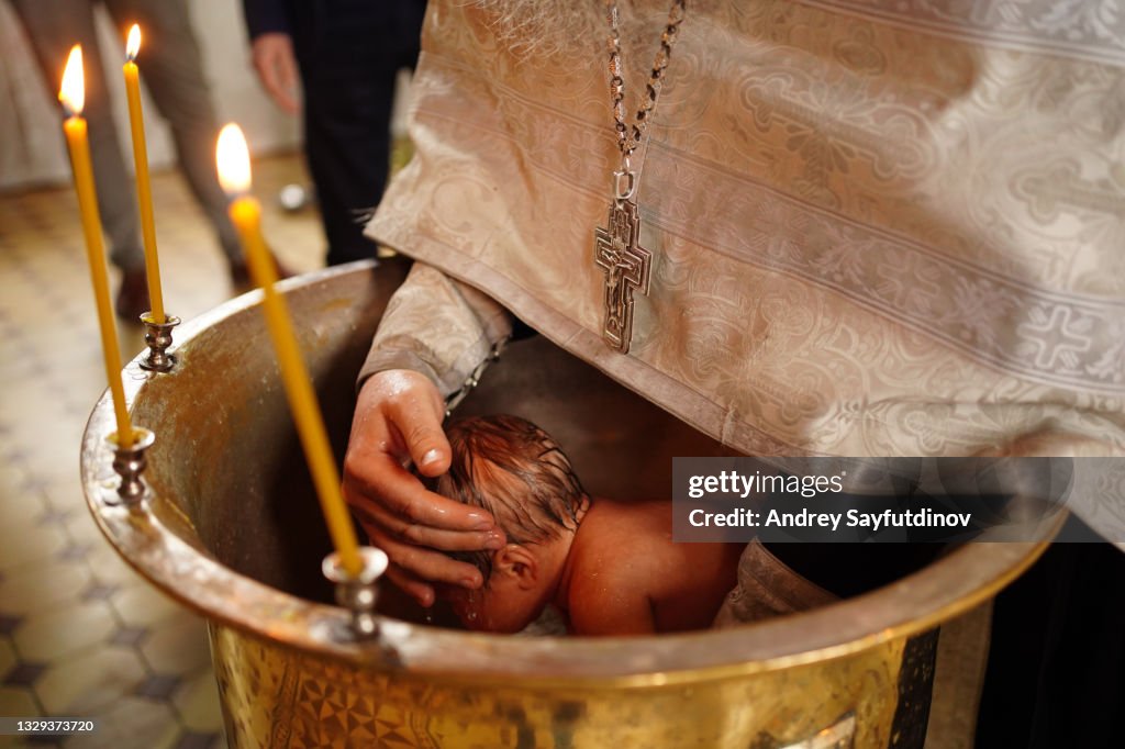 The baby is lowered into the font at the baptism in the church.