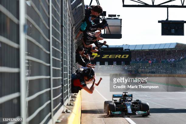 Race winner Lewis Hamilton of Great Britain driving the Mercedes AMG Petronas F1 Team Mercedes W12 passes his team celebrating on the pitwall during...