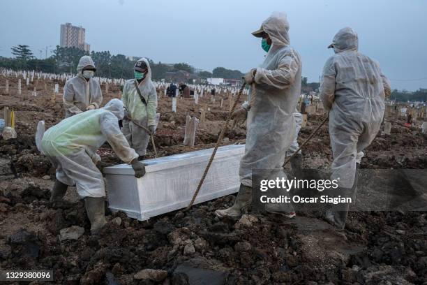 Funeral workers bury the coffins of Covid-19 victims at Rorotan cemetery on July 18, 2021 in North Jakarta, Indonesia. Indonesia has imposed...