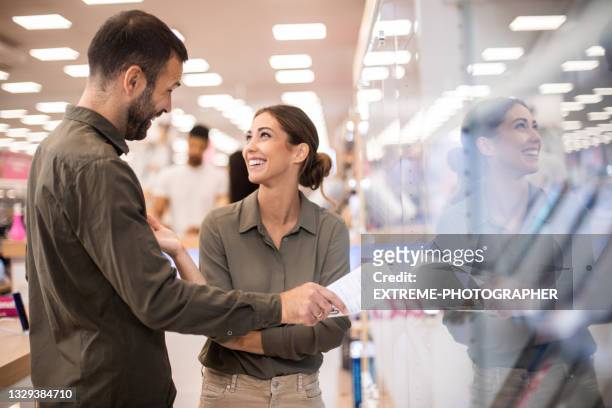 two salespersons seen in front of shelf with smart phones - appliance store stockfoto's en -beelden