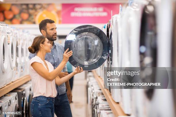 junges paar auf der suche nach einer richtigen trocknungsmaschine - haushaltsausrüstung stock-fotos und bilder