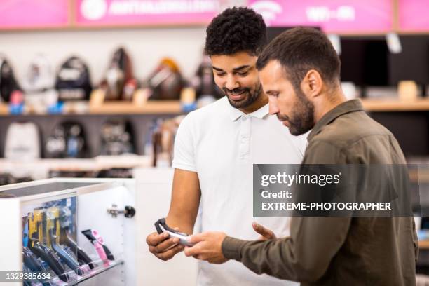 salesman and a male buyer looking at a hair trimmer - electrical shop stock pictures, royalty-free photos & images