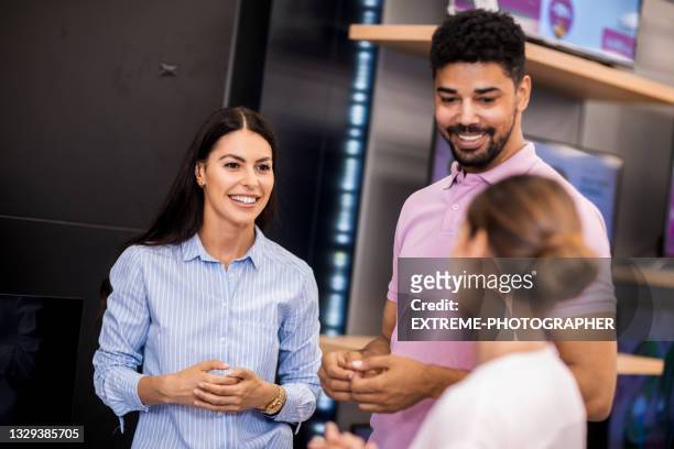 young couple and a saleswoman - retailer shopping customer tv stockfoto's en -beelden