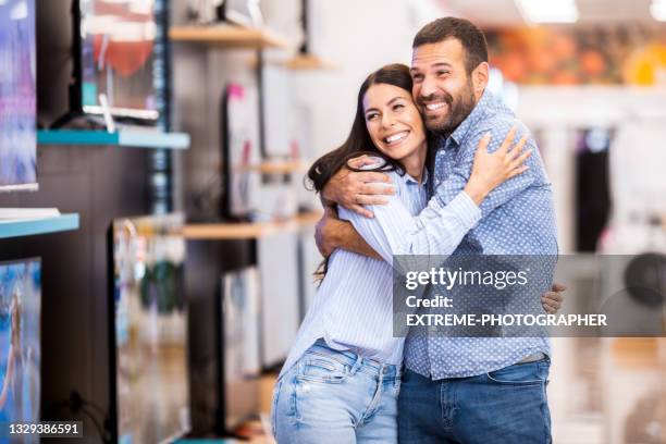 happy couple enjoys shopping for their new home - retailer shopping customer tv stockfoto's en -beelden