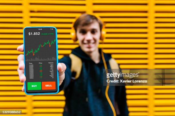 man showing smart phone screen with stock market investment app - stockbrokers fotografías e imágenes de stock