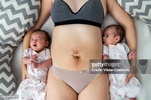 madre con estrías en el abdomen por el embarazo con sus bebés - baby touching belly fotografías e imágenes de stock