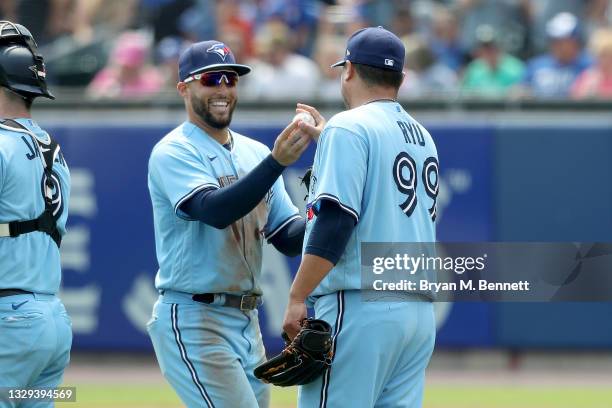 George Springer of the Toronto Blue Jays hands teammate Hyun Jin Ryu a ball after defeating the Texas Rangers 5-0 in game one of a doubleheader at...