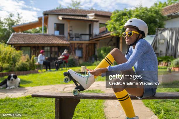 an afro-american teenage girl putting on roller skates - jamaicansk stock pictures, royalty-free photos & images