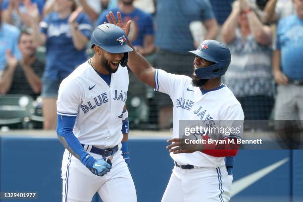 Lourdes Gurriel Jr. #13 of the Toronto Blue Jays celebrates with teammate Teoscar Hernandez after hitting a grand slam home run during the first...