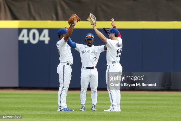 Teammates Teoscar Hernandez, Jonathan Davis, and Randal Grichuk, all of the Toronto Blue Jays, celebrate after defeating the Texas Rangers 10-0 in...