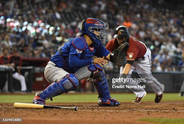 Robinson Chirinos of the Chicago Cubs waits for the throw from Anthony Rizzo to get a force out at home plate as Nick Ahmed of the Arizona...
