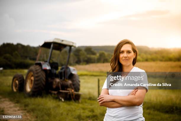 porträt einer professionellen frau auf dem gebiet der agronomie vor einem traktor - portrait team natürlich stock-fotos und bilder