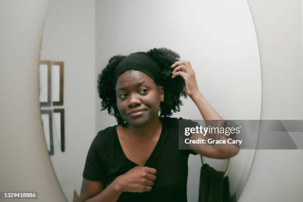 woman tends to her hair in powder room mirror - african woman hair stock-fotos und bilder