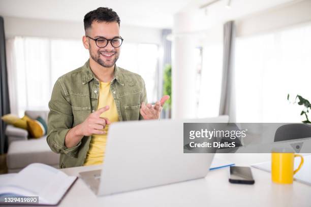 glücklicher junger mann mit einer online-beratung zu hause. - vorstellungsgespräch stock-fotos und bilder