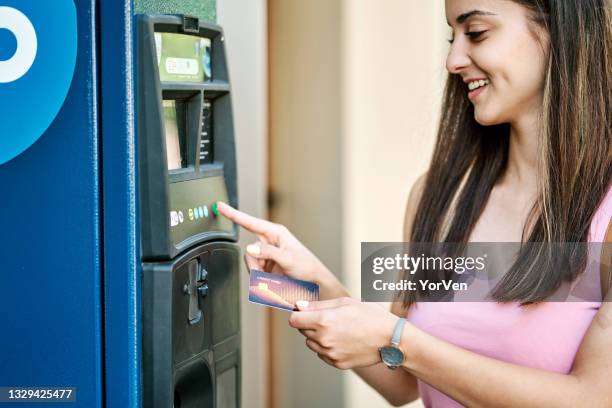 mujer joven usando la máquina de estacionamiento - parking meter fotografías e imágenes de stock