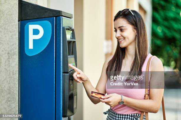 mujer joven usando la máquina de estacionamiento - parking meter fotografías e imágenes de stock