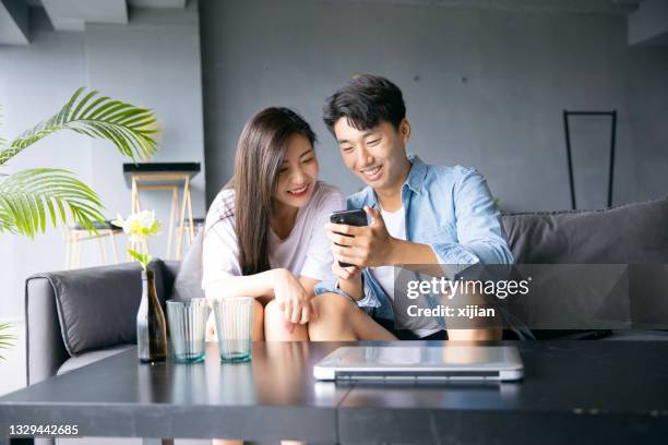 happy young couple share information on mobile phone - asian couple imagens e fotografias de stock