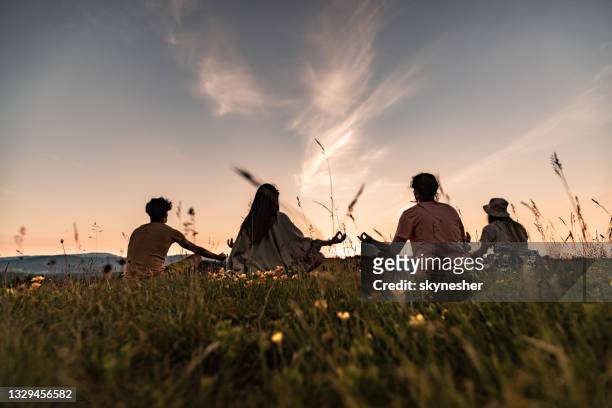 back view of relaxed people meditating in nature at sunset. - chan stock pictures, royalty-free photos & images