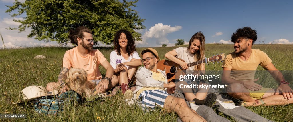 Panoramic view of happy friends enjoying in spring day in a meadow.