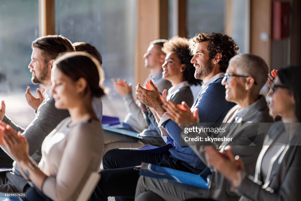 Large group of happy entrepreneurs applauding on a seminar in board room.