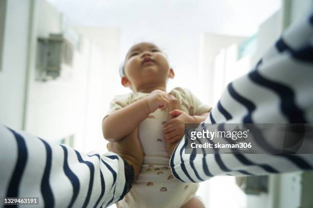 selective focus wide angle personal perspective point of view of hand  asian man lifting daughter against the sky - chambre nouveau né famille photos et images de collection