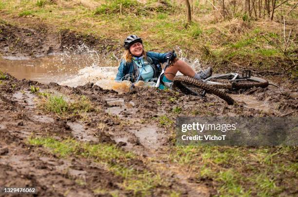 giovane mountain biker donna caduta in una pozzanghera fangosa durante una competizione - mud foto e immagini stock