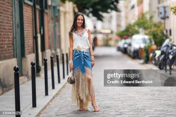 Alba Garavito Torre wears blue and silver beaded pearl necklaces, a white tank top, a pearl bracelet, a blue floral print fringed Spanish Manila...