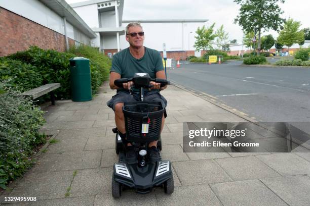 cheerful looking adult male riding his mobility scooter away from the vaccination after being vaccinated against covid 19 - motor cart stock pictures, royalty-free photos & images