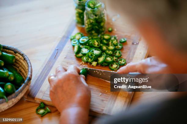 woman preparing pickles with jalapeno peppers - sliced pickles stockfoto's en -beelden