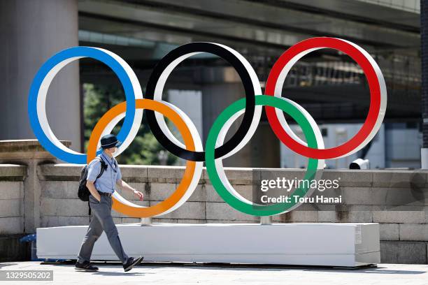 Man wearing a face mask walks past the Olympic Rings ahead of the Tokyo 2020 Olympic Games on July 19, 2021 in Tokyo, Japan.