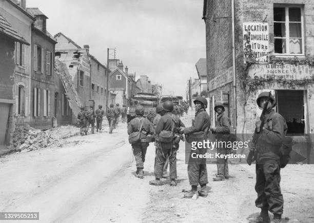 Column of infantrymen from units of the 502nd and 506th regiments of the 101st Airborne Division enter the town of Sainte-Mere-Eglise on 11th June...