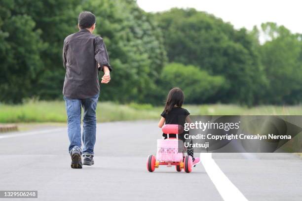 father is running while his child is riding on a three wheeled tyre bike - 父の日　日本 ストックフォトと画像