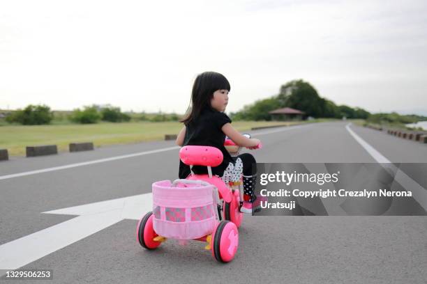 child learning to ride on a three wheeled tyre balance bicycle - filipino tricycle stock pictures, royalty-free photos & images