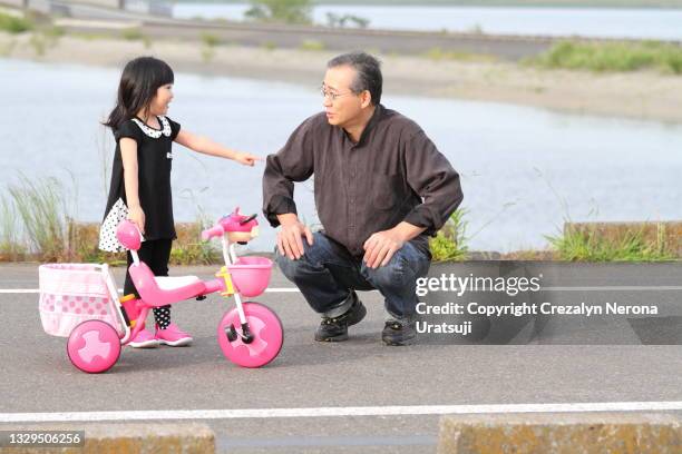 father teaching his child to ride on a three wheeled tyre bike - 父の日　日本 ストックフォトと画像