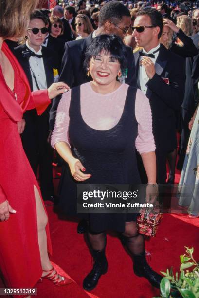 American comedian Roseanne Barr, wearing a black dress with a scooped neckline over a pale pink long-sleeved crew-neck top, attends the 46th Annual...