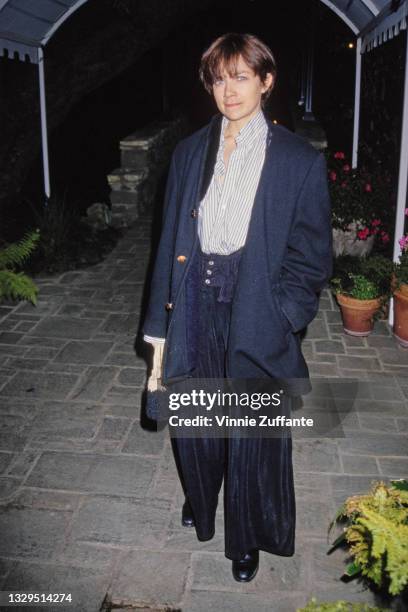 American actress Justine Bateman, wearing a long navy blue jacket over a blue-and-white striped blouse, with baggy navy blue trousers, location...