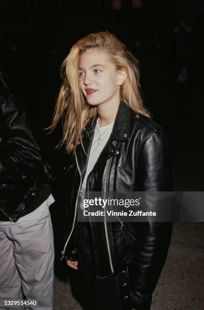 American actress Drew Barrymore, wearing a white t-shirt beneath a black leather jacket, attends the Century City premiere of 'Longtime Companion',...
