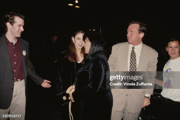 Kim Silva, assistant to Tom Arnold, with American comedian Roseanne Arnold, wearing a velvet outfit with a beaded necklace, and Roseanne's husband,...