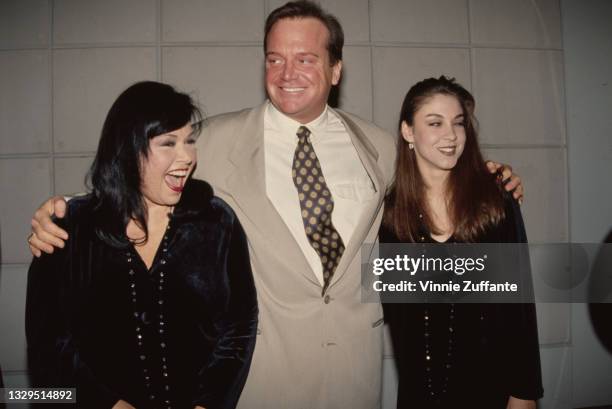 American comedian Roseanne Arnold, wearing a velvet outfit with a beaded necklace, while her husband, American actor and comedian Tom Arnold, and...