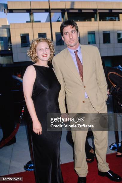 American actress Drew Barrymore, wearing a black sleeveless evening gown, and American actor Luke Wilson, wearing a beige suit with a blue shirt and...