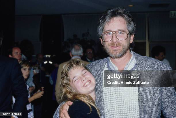 American actress Drew Barrymore and American film director Steven Spielberg, wearing a grey sports jacket over a checked crew neck sweater with his...