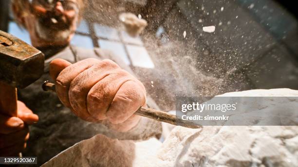 stonemason chiselling surface of white stone - sculptor stock pictures, royalty-free photos & images